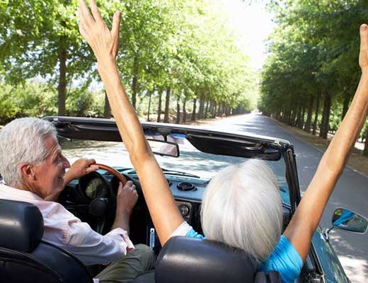 Image of Older Couple Driving a Convertible Down the Road